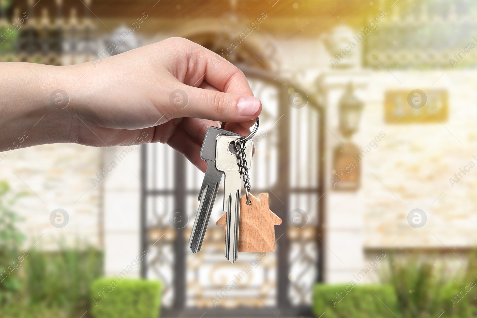 Image of Woman holding keys near house outdoors, closeup