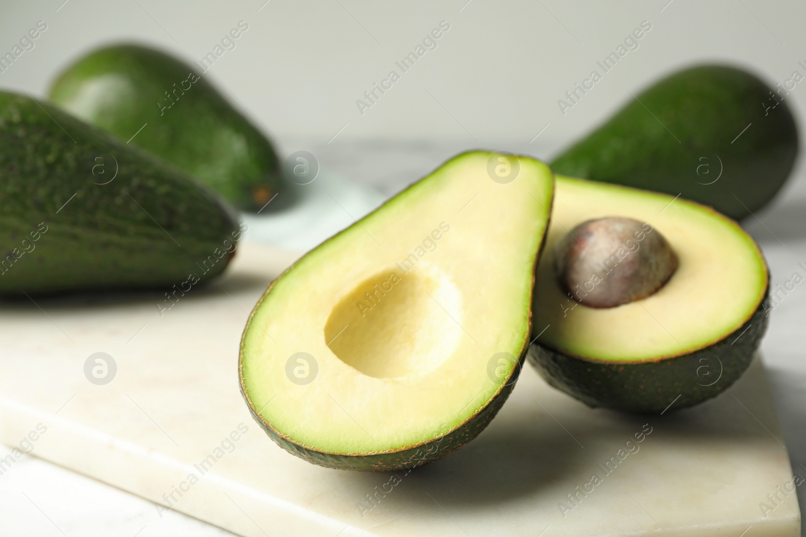 Photo of Delicious ripe avocados on table against light background