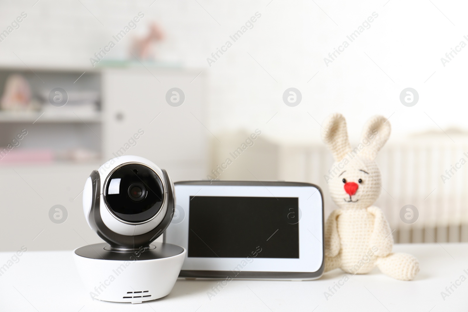 Photo of Baby monitor with camera and toy on table in room. Video nanny