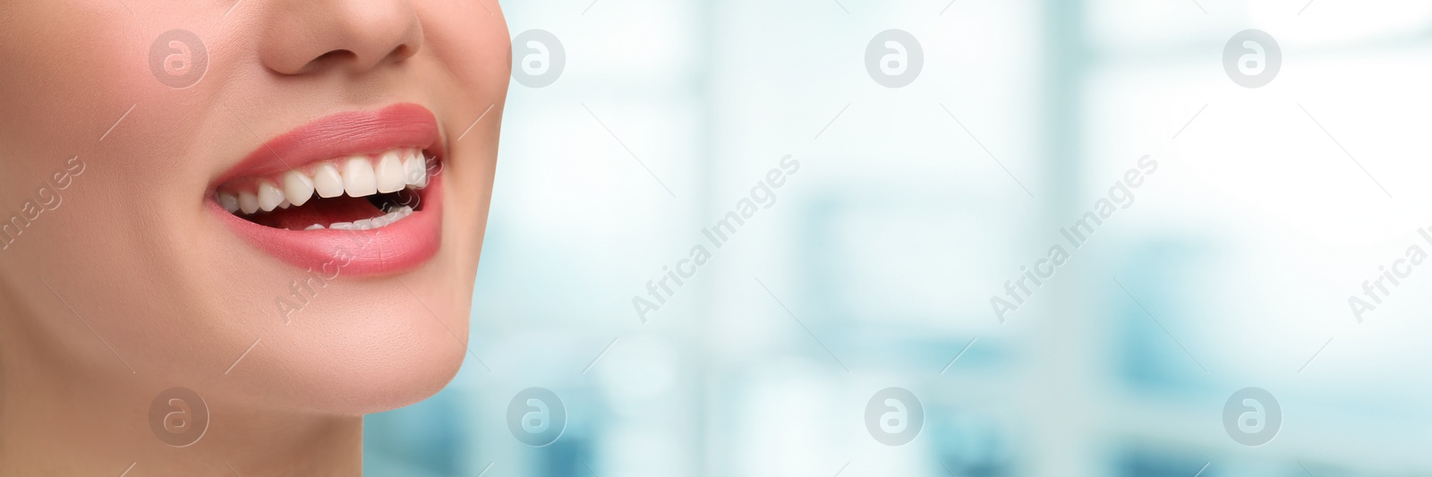 Image of Woman with clean teeth smiling on blurred background, closeup. Banner design with space for text