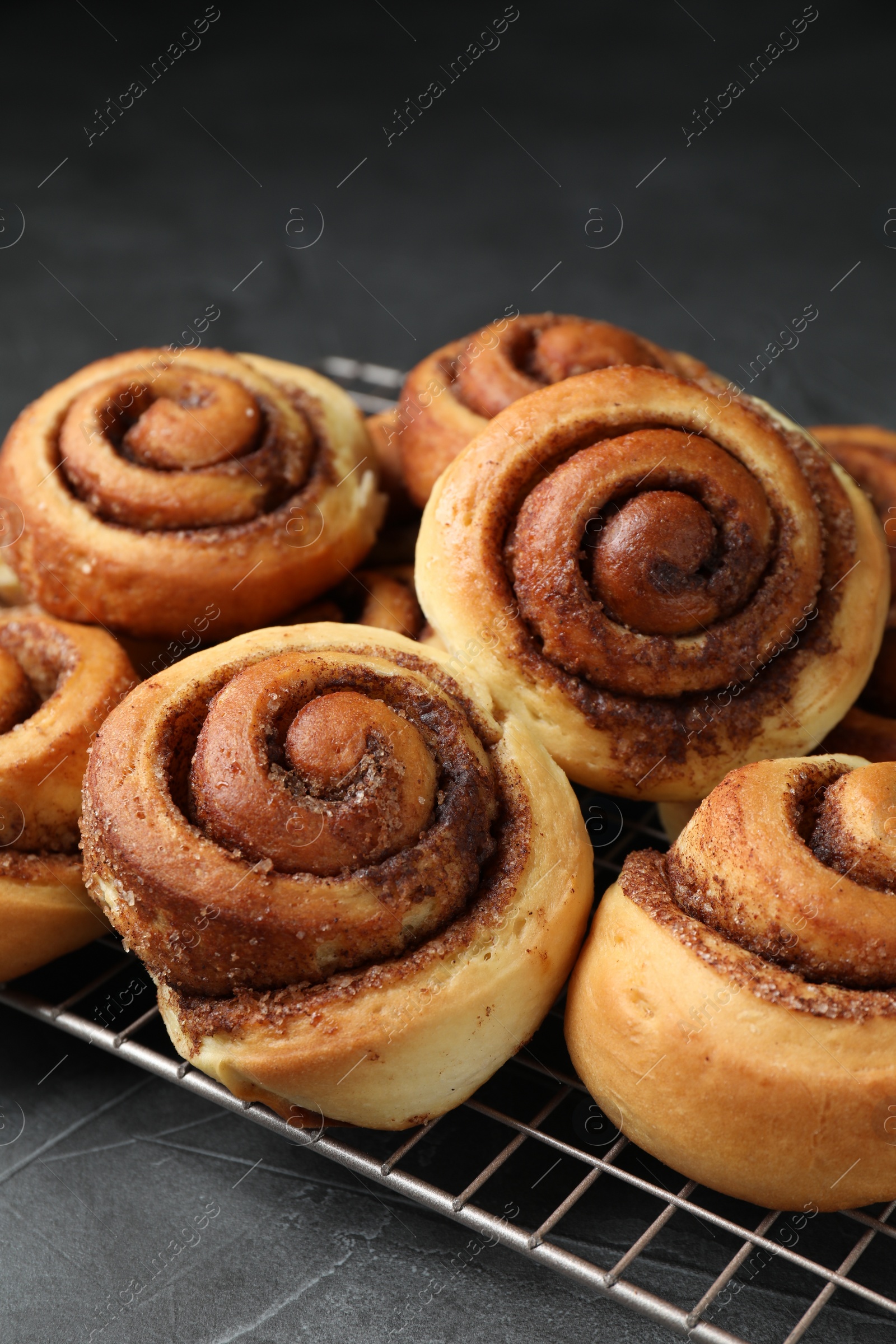 Photo of Tasty cinnamon rolls on black table, closeup