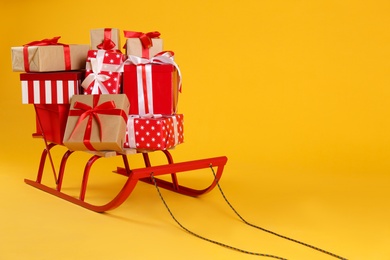 Sleigh with gift boxes on yellow background. Space for text