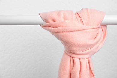 Photo of Pink scarf on wardrobe rack against light background, space for text. Autumn clothes