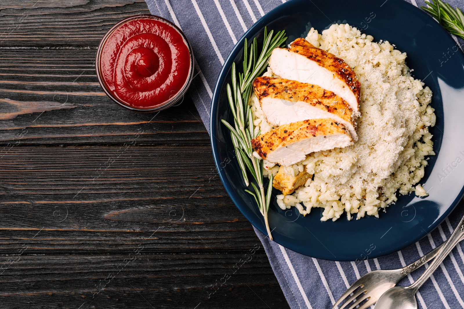 Image of Delicious chicken risotto served on black wooden table, flat lay with space for text. Food photography  