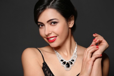 Beautiful young woman with elegant jewelry on dark background