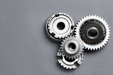 Photo of Different stainless steel gears on grey background, flat lay. Space for text