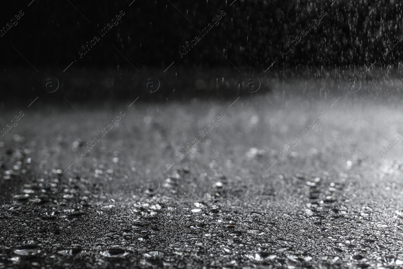 Photo of Rain drops falling down against dark background