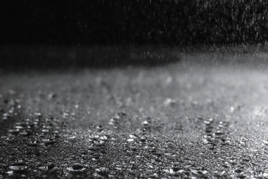 Photo of Rain drops falling down against dark background