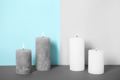 Photo of Decorative wax candles on table against color background