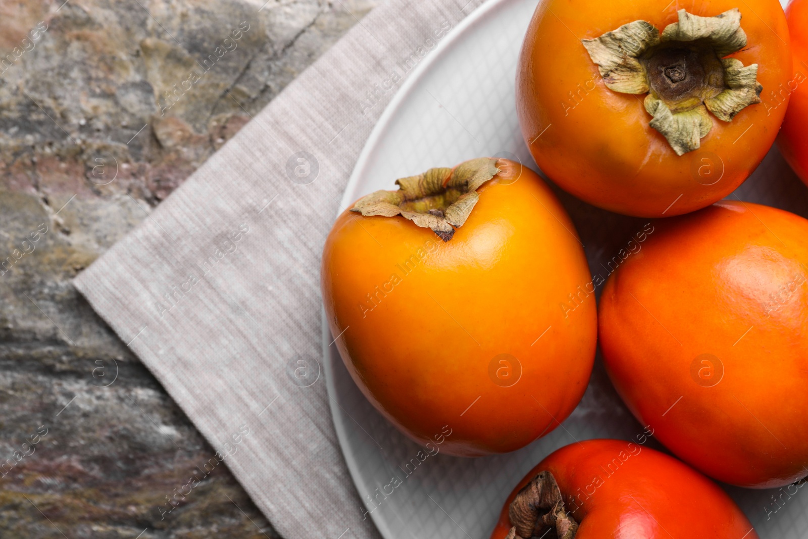 Photo of Delicious ripe persimmons on textured table, top view. Space for text