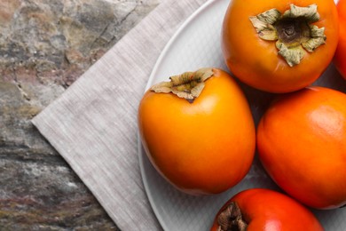 Photo of Delicious ripe persimmons on textured table, top view. Space for text