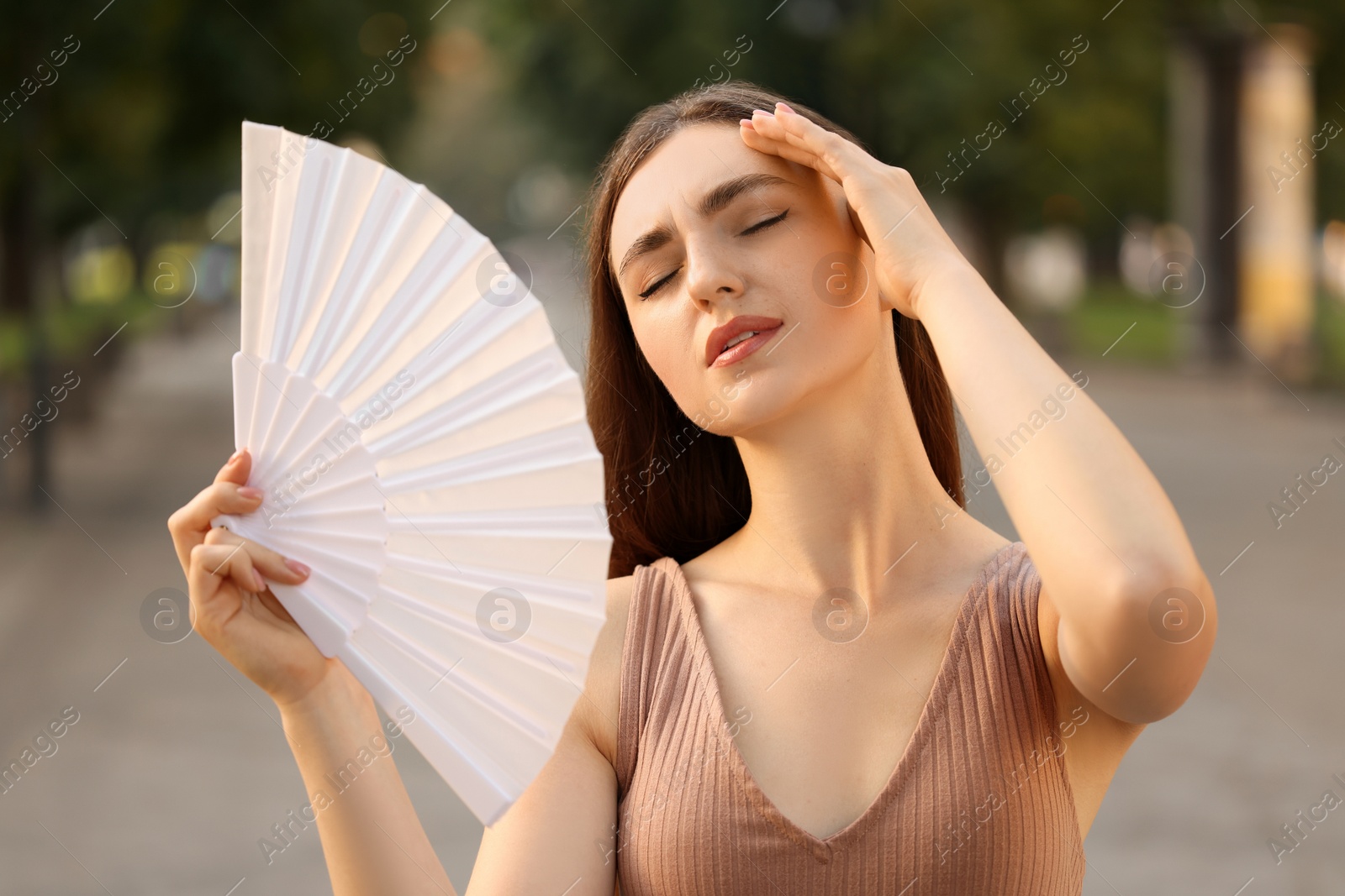 Photo of Woman with hand fan suffering from heat outdoors