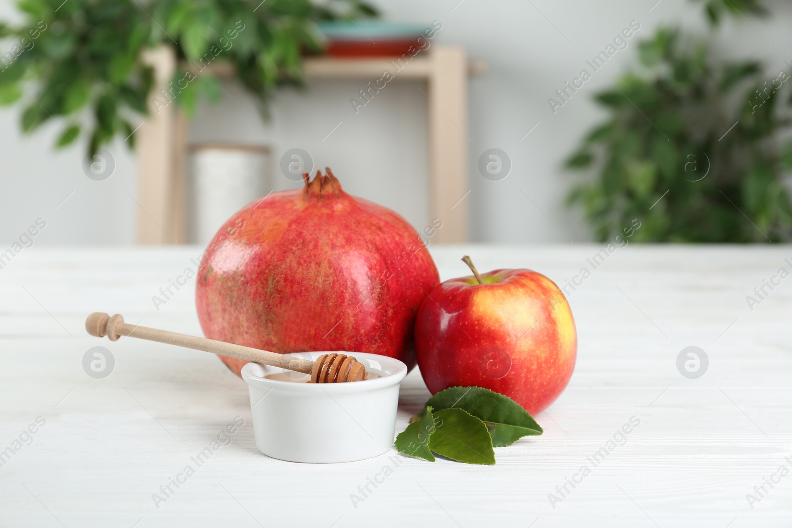 Photo of Honey, apple and pomegranate on white wooden table. Rosh Hashanah holiday