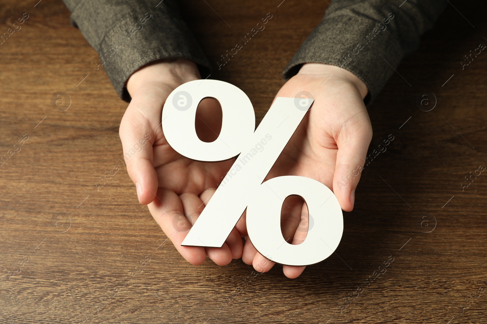 Photo of Man holding percent sign at wooden table, closeup