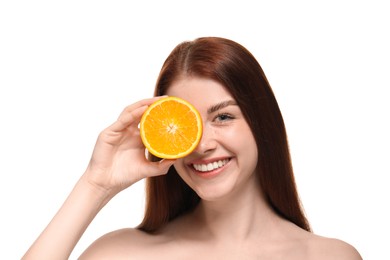 Smiling woman covering eye with half of orange on white background