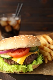 Photo of Delicious burger, soda drink and french fries served on wooden table, closeup