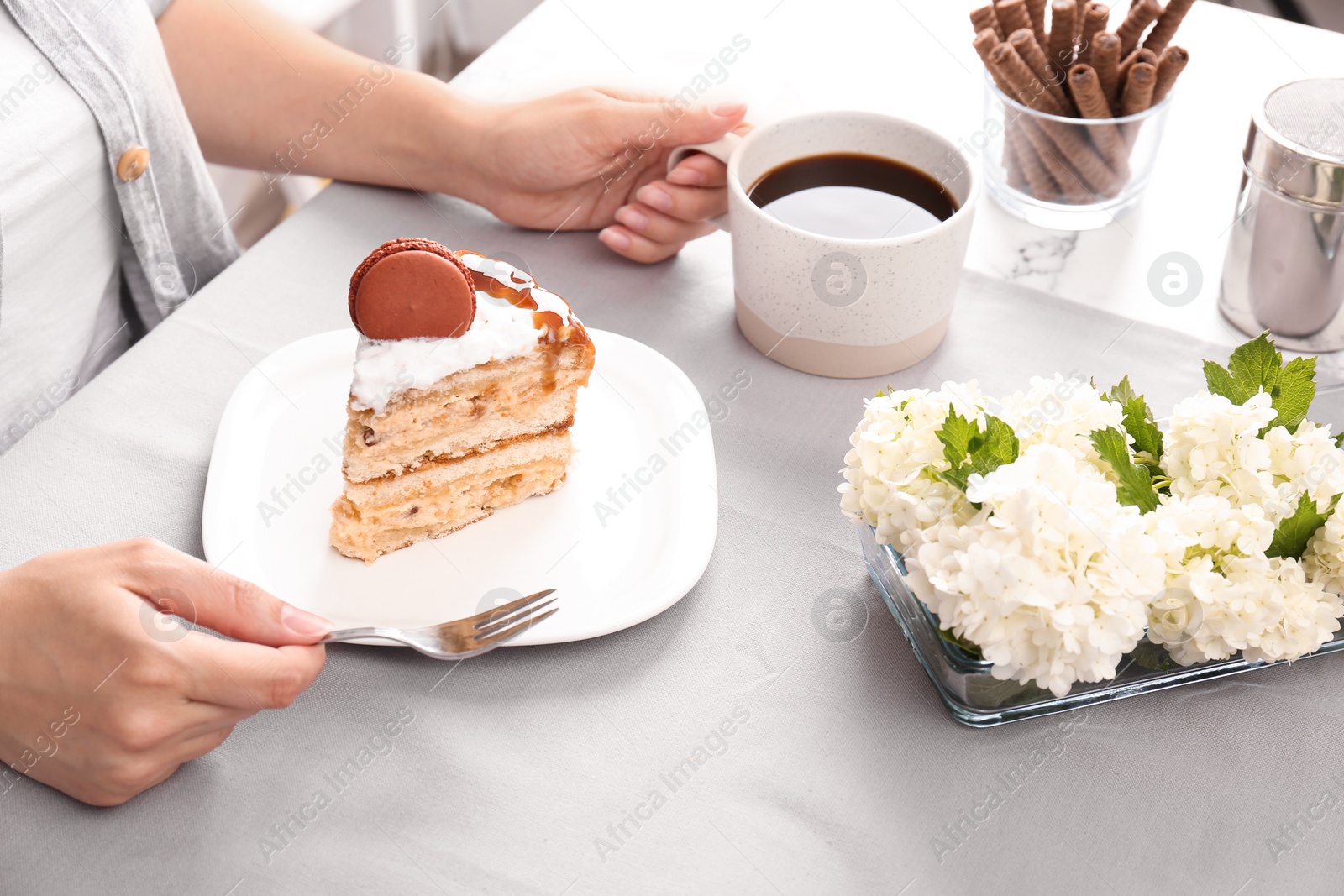 Photo of Woman eating delicious homemade cake with caramel sauce at table