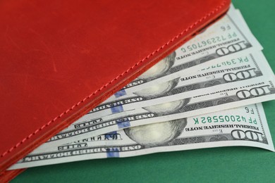 Photo of Money exchange. Wallet with dollar banknotes on green background, closeup