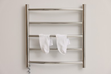 Photo of Heated towel rail with socks on white wall