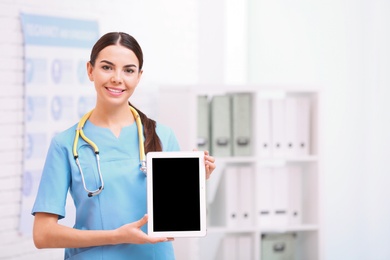 Portrait of medical assistant with stethoscope and tablet in hospital. Space for text