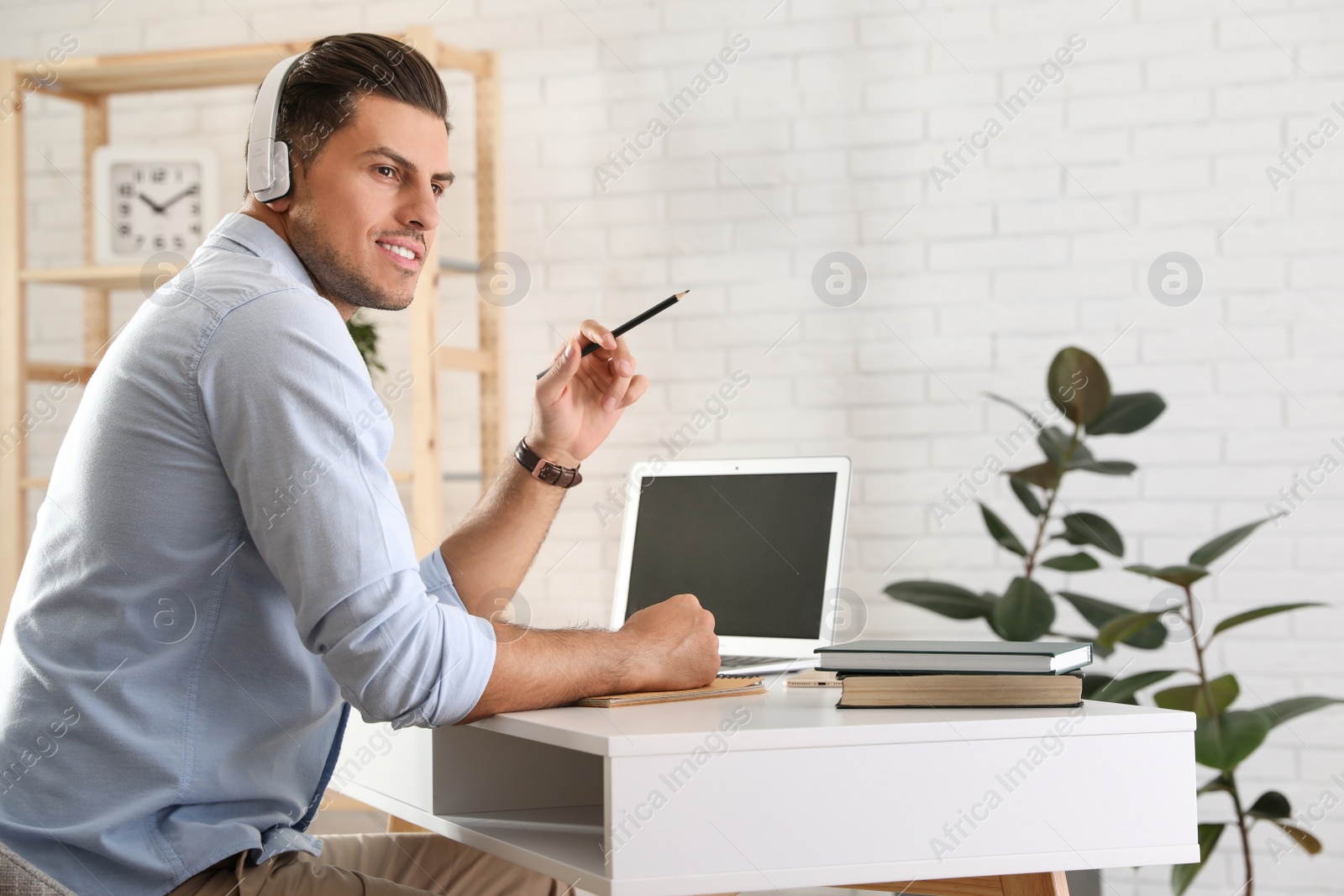 Photo of Man listening to audiobook at table with laptop