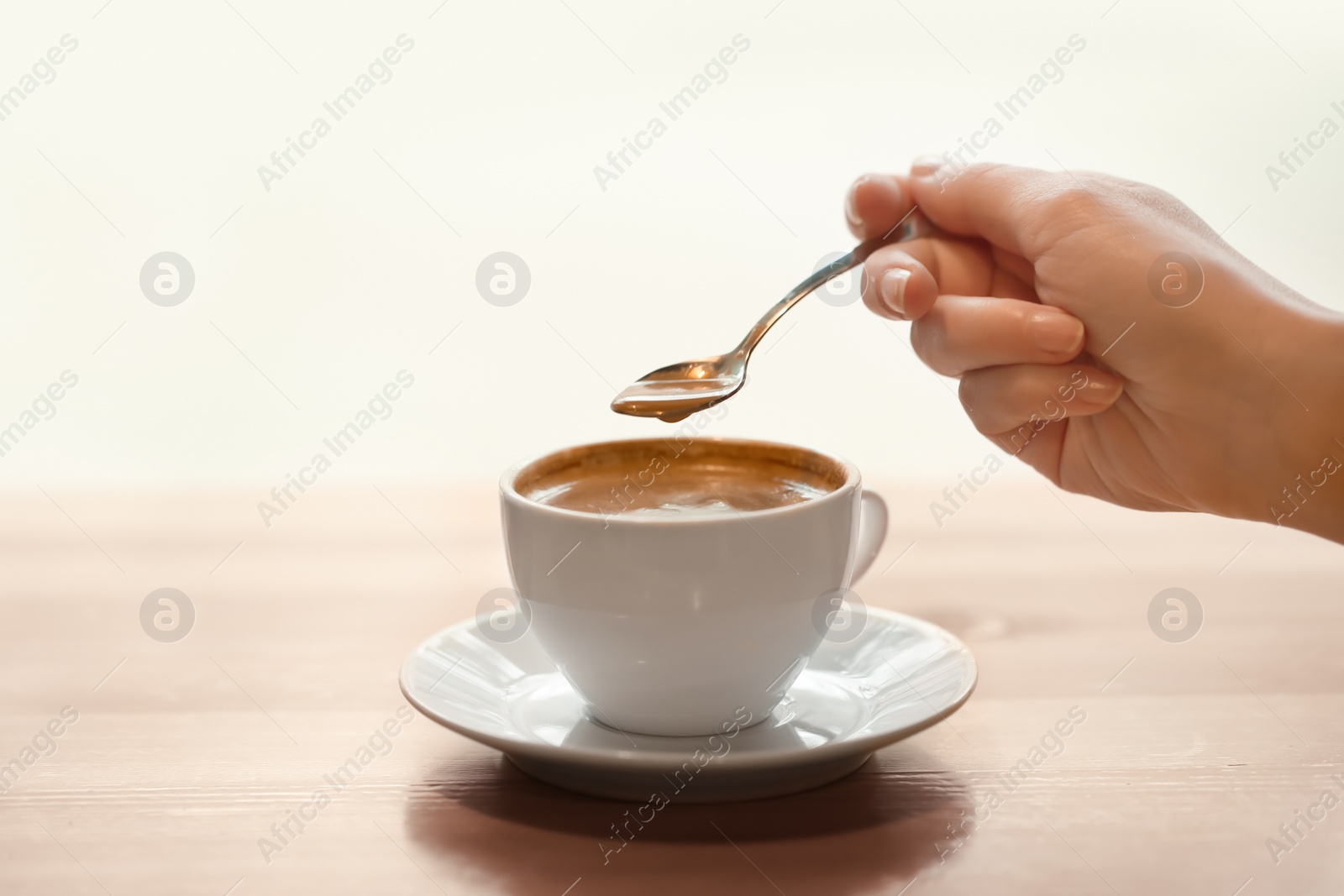 Photo of Woman with cup of aromatic coffee at wooden table