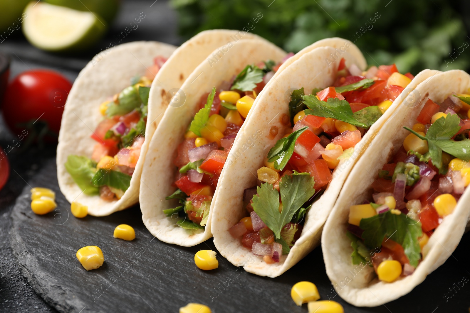 Photo of Tasty tacos with vegetables on black table, closeup