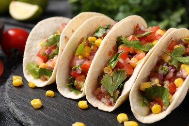 Photo of Tasty tacos with vegetables on black table, closeup