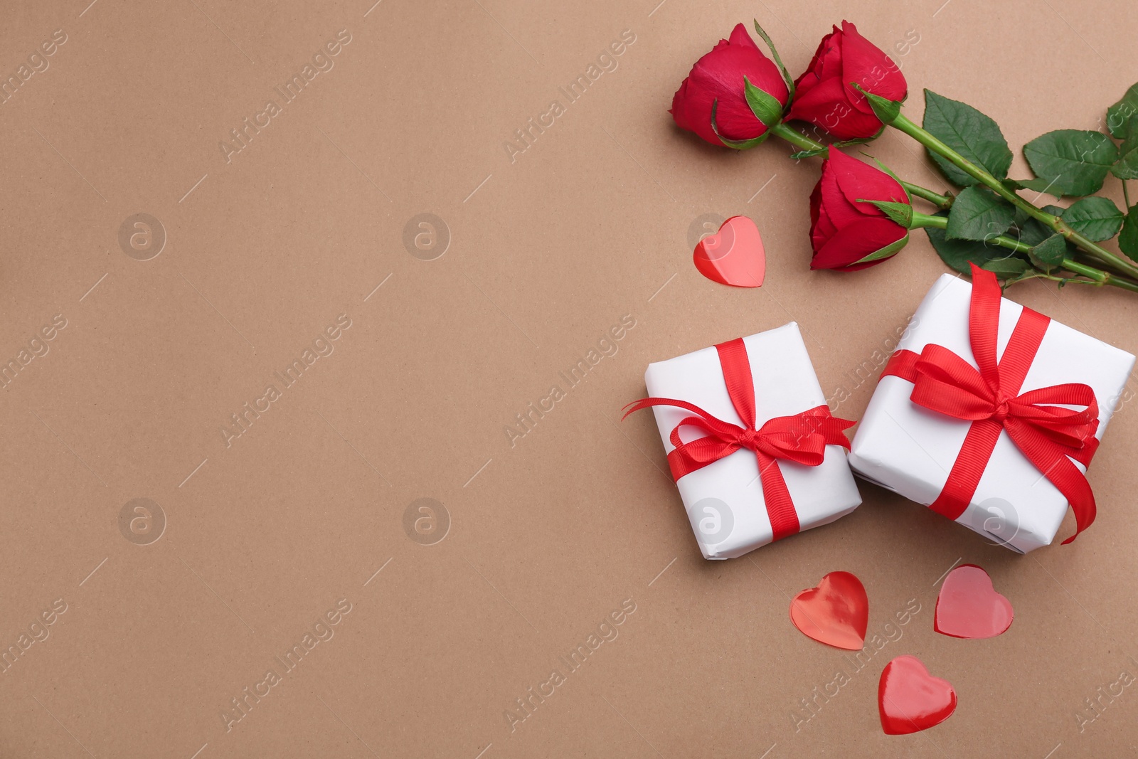 Photo of Gift boxes, roses and hearts on brown background, flat lay with space for text. Valentine's Day celebration