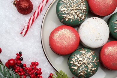 Photo of Beautifully decorated Christmas macarons, candy cane and festive decor on snow, flat lay