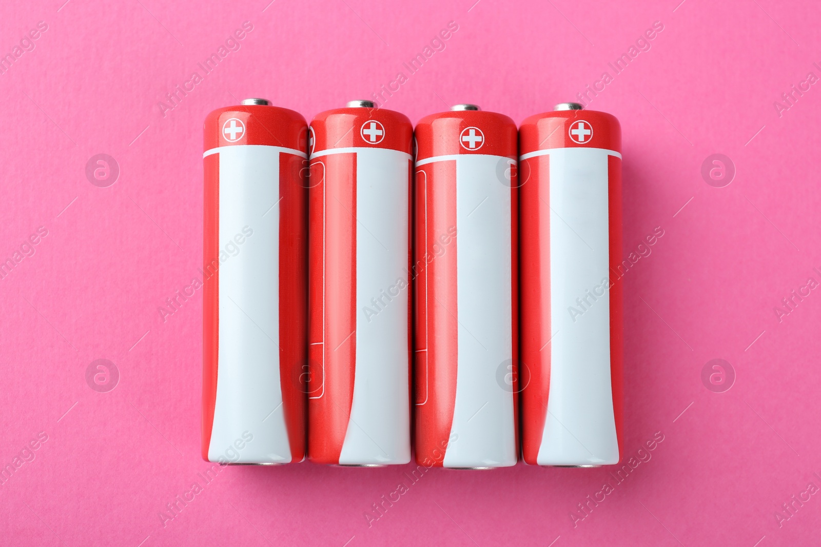 Image of New AA batteries on pink background, flat lay