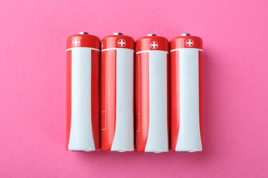 Image of New AA batteries on pink background, flat lay