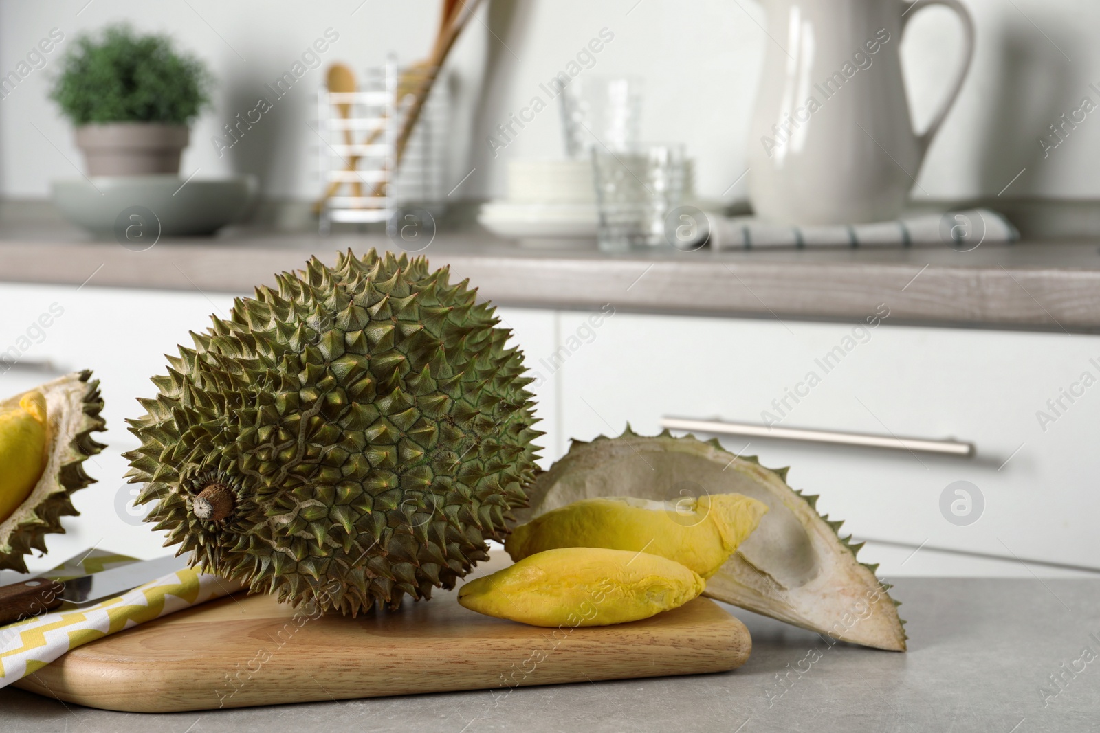 Photo of Fresh ripe durian fruits on grey table in kitchen, space for text