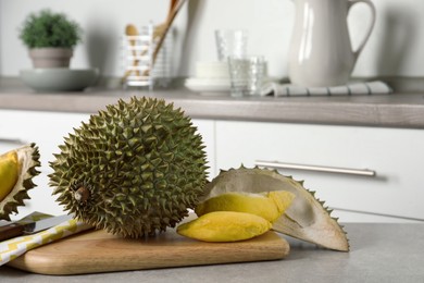 Photo of Fresh ripe durian fruits on grey table in kitchen, space for text