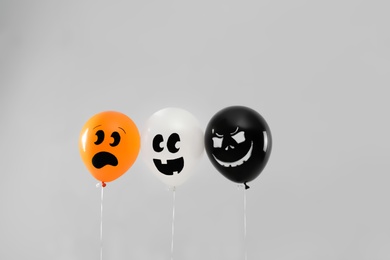 Photo of Spooky balloons for Halloween party on light grey background