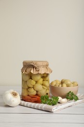 Photo of Tasty pickled mushrooms and spices on white wooden table