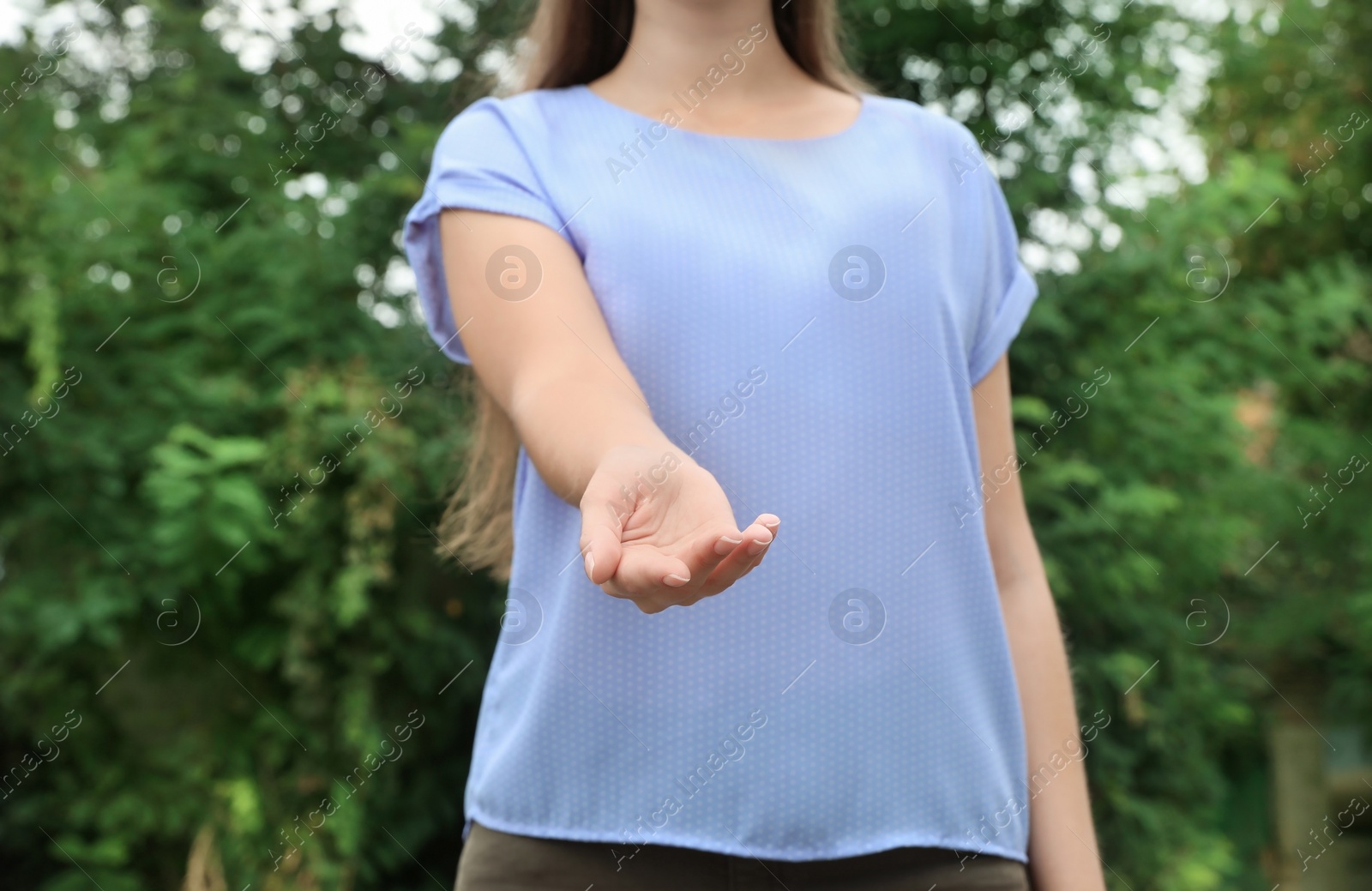 Photo of Woman giving helping hand on blurred background outdoors