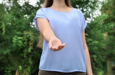 Woman giving helping hand on blurred background outdoors