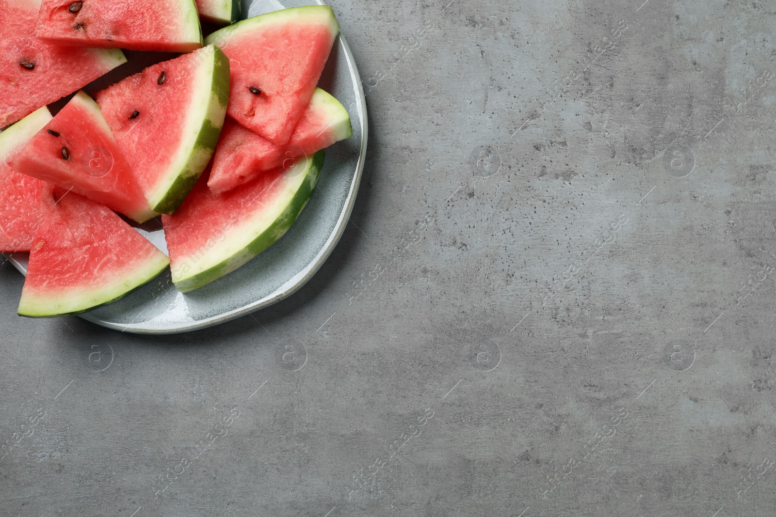 Photo of Delicious fresh watermelon slices on grey table, top view. Space for text