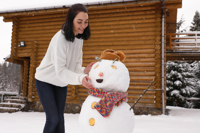 Photo of Young woman near funny snowman outdoors. Winter vacation