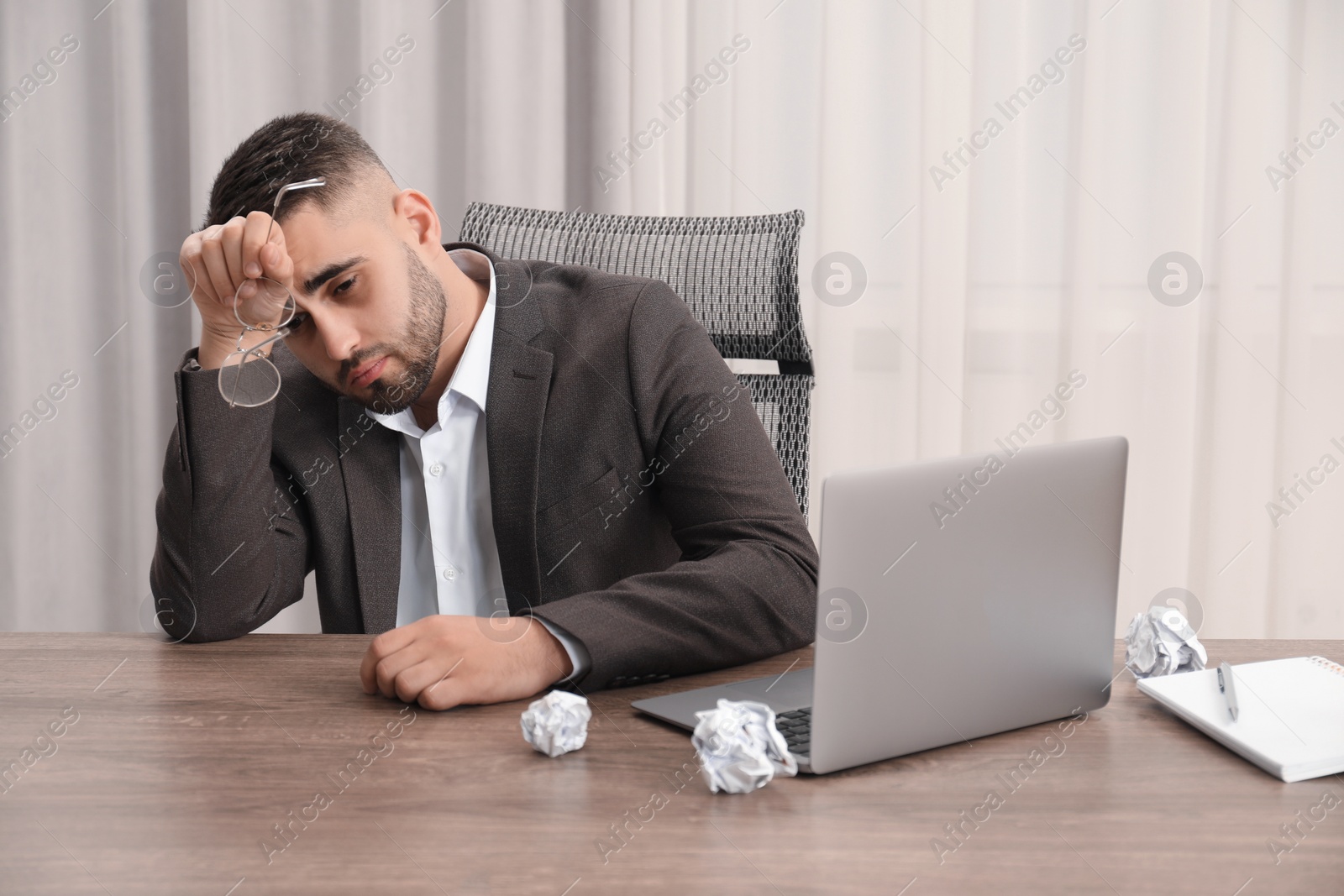 Photo of Tired sad businessman sitting at table in office