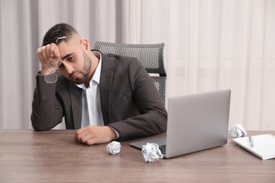 Photo of Tired sad businessman sitting at table in office