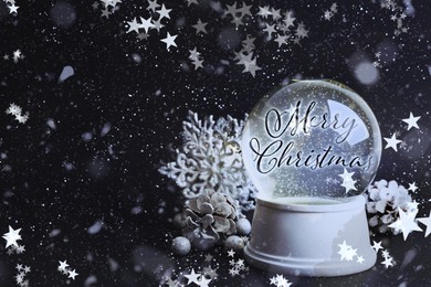 Image of Beautiful snow globe with phrase Merry Christmas and decorations on black background. Space for text
