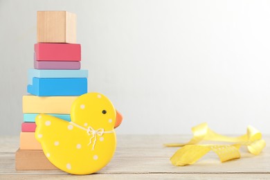 Photo of Tasty cookie in shape of cute duckling, pyramid and ribbon on white wooden table. Space for text