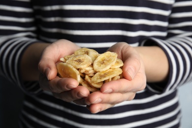 Photo of Woman holding handful of sweet banana slices, closeup. Dried fruit as healthy snack