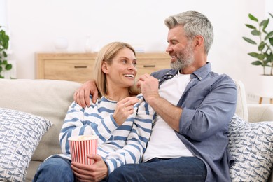 Photo of Happy affectionate couple with popcorn on sofa indoors. Romantic date
