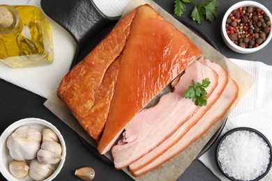 Photo of Flat lay composition with delicious smoked bacon on black table