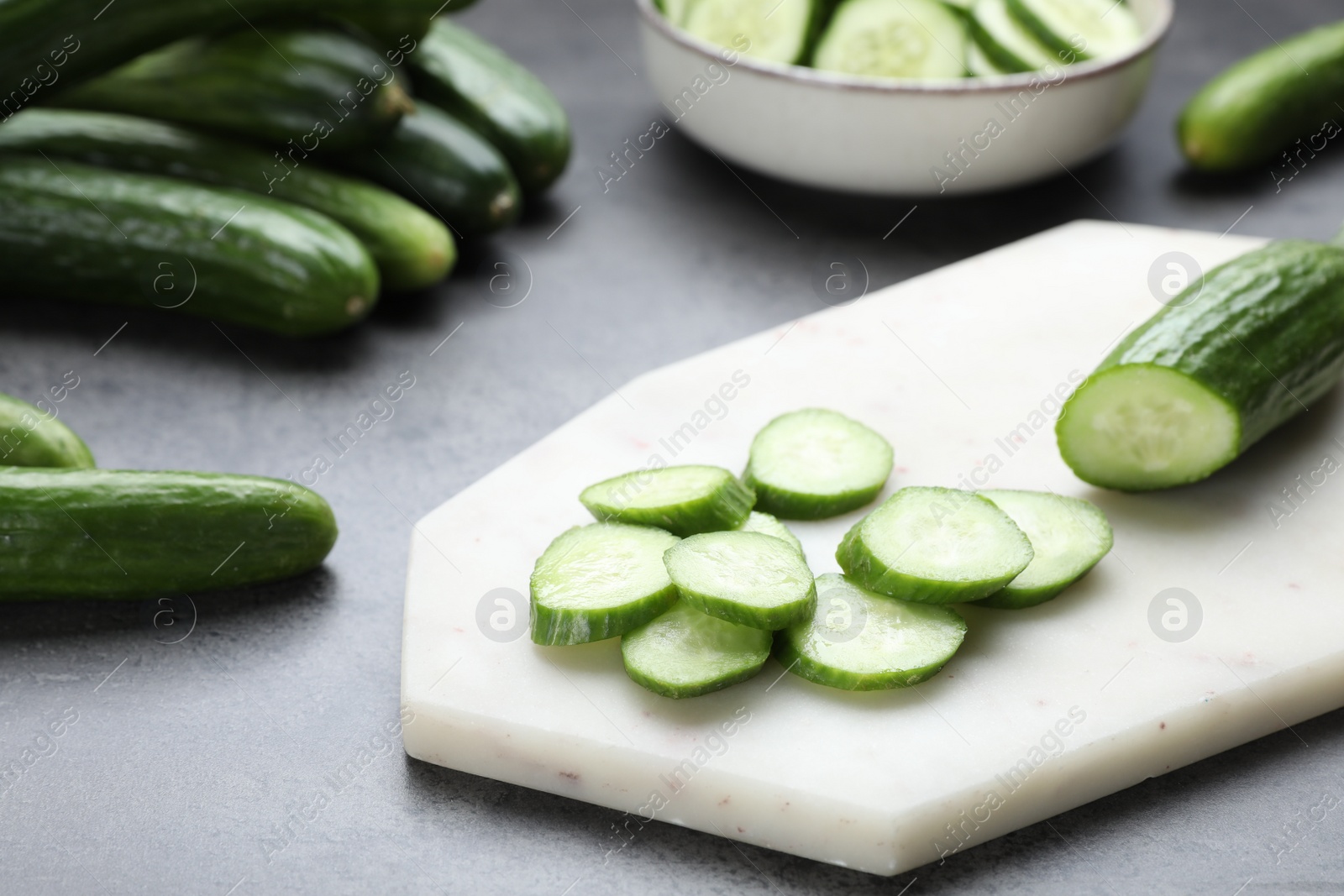 Photo of Whole and cut fresh ripe cucumbers on grey table