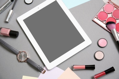 Composition with tablet and makeup products for woman on grey background