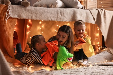 Photo of Mother and her children playing with toys in play tent at home